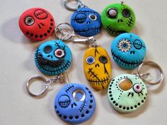 six different colored skull key chains with eyes and noses painted on them, all sitting in a row