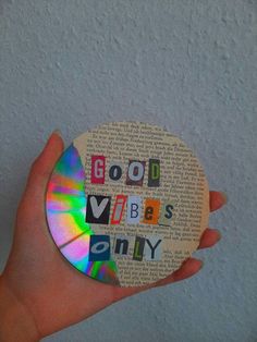 a person holding a cd with the words good vibes on it in front of a white wall