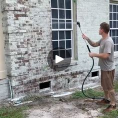 a man using a pressure washer to clean the windows in an old brick building