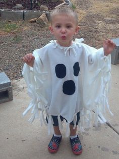 a little boy dressed up as a cow in a white ponchy with black spots