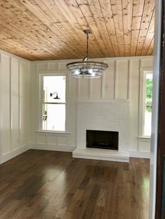 an empty living room with hard wood flooring and white painted walls on either side of the fireplace