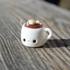 a small white cup with nuts in it sitting on a wooden table next to a keychain