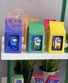 colorful boxes with elephants painted on them sitting on a shelf next to potted plants