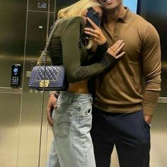 a man and woman standing next to each other in front of an elevator holding cell phones