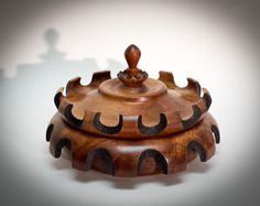 a wooden container with an intricate design on it's lid and handle, sitting on a white surface