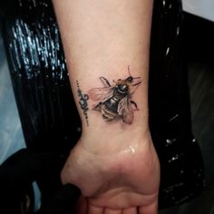 a small tattoo of a bee on the foot with words written below it and an arrow in the middle