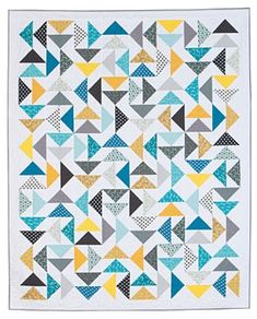 a quilt made with triangles and dots in blue, grey, yellow and white colors