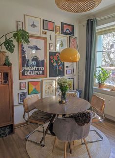 a dining room table with chairs and pictures on the wall in front of it's windows