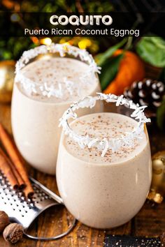 two glasses filled with drink sitting on top of a table next to cinnamon sticks and christmas decorations