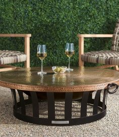 two chairs and a table with wine glasses on it in front of a green wall