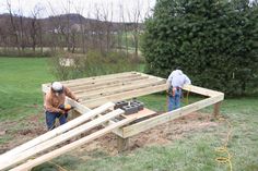 two men working on building a house in the yard with wood beams attached to it