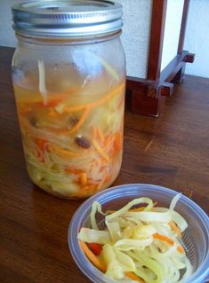 a glass jar filled with food sitting on top of a wooden table next to a plastic container