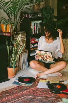 a woman is sitting on the floor with her record player and records in front of her