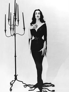 a black and white photo of a woman standing next to a candelabra