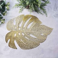 a gold leaf shaped metal object sitting on top of a table next to some plants