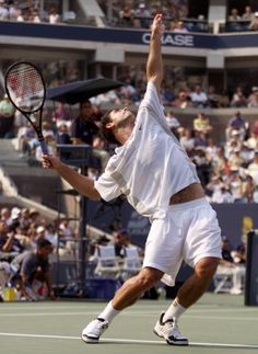 a man holding a tennis racquet on top of a tennis court in front of a crowd