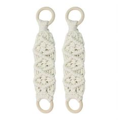 two white crocheted bottle holders with wooden rings on each one and an o ring in the middle