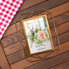 a photo frame with flowers on it sitting next to a table cloth and some other items