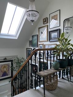 a staircase with pictures on the wall and chandelier hanging from it's ceiling