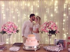 a man and woman kissing in front of a table full of cakes, cupcakes and flowers