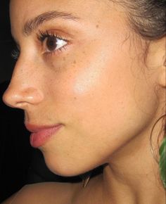 a close up of a woman with freckles on her face and earrings