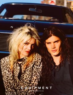 two people sitting next to each other in front of a car with the words equipment on it