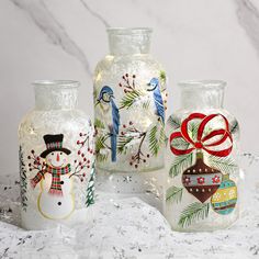 three glass vases decorated with christmas decorations