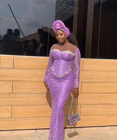 Pretty wedding guest in Lilac Asoebi with Gele and multicolored purse Lace Gown Styles Aso Ebi, Gown Dress For Women, Lace Gown Dress, Lace Asoebi Styles, Latest Lace Styles, Lace Styles For Wedding, Nigerian Lace Dress, Nigerian Dress Styles, Aso Ebi Dresses