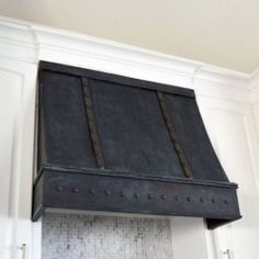 a black stove top oven mounted to the side of a white kitchen wall above a sink