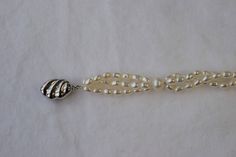 a white beaded bracelet with silver beads and a ball clasp on a white background