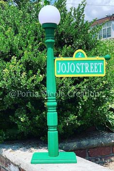 a green street sign sitting on the side of a brick wall in front of bushes