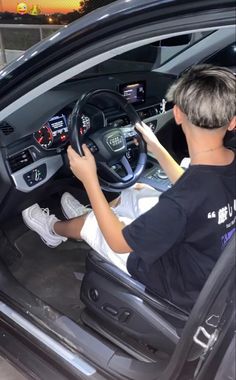 a man sitting in the driver's seat of a car with his hands on the steering wheel