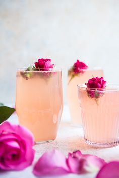 three glasses filled with liquid and pink flowers