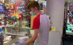 a man wearing a face mask in front of a store filled with toys and other items