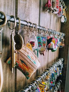 a bunch of key chains hanging on a wooden wall with many different colors and designs