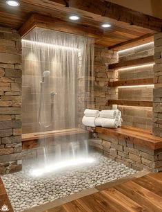 a bathroom with stone walls and a waterfall in the center, surrounded by wood flooring