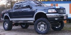 a large black truck parked on top of a dirt road