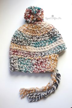 a multicolored knitted hat laying on top of a white surface