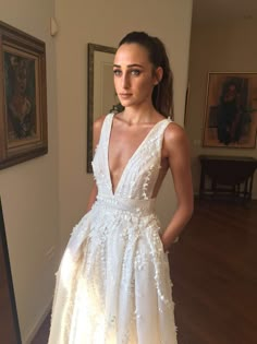 a woman wearing a white dress standing in front of a mirror