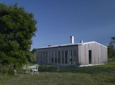 a small wooden house sitting on top of a lush green field next to a tree