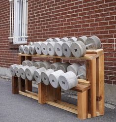 several rolls of toilet paper are stacked up on a wooden rack in front of a brick wall