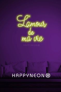 a neon sign that reads happynon on the side of a purple wall next to a couch