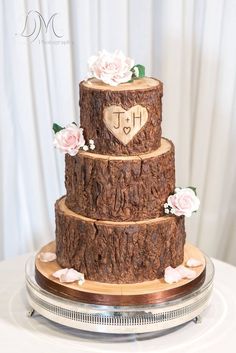 a three tiered wedding cake decorated with wood slices and flowers