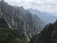 the mountains are covered with green trees and rocks