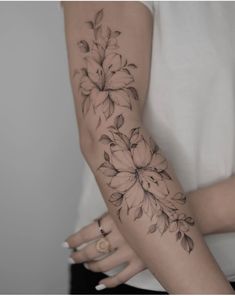 a woman's arm with flowers tattooed on the left side of her arm and wrist