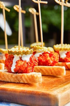 small appetizers with toothpicks are sitting on a cutting board, ready to be eaten