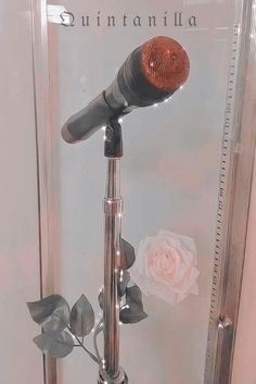 a silver and red microphone on top of a stand with flowers in front of it