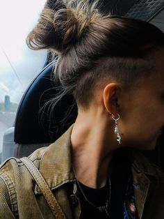 a woman sitting in a car with her hair pulled back and earrings hanging from her ear