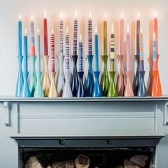 there are many colorful candles on top of the fireplace