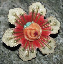 a flower brooch sitting on top of a granite counter next to a stone wall